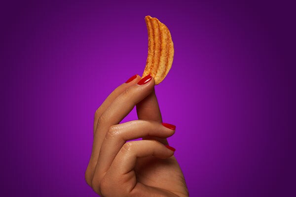 Hand holding a Pringles Groovz crisp