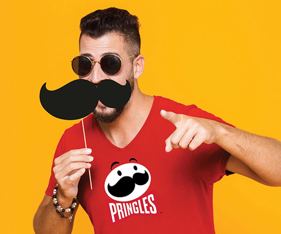 A man holding a fake mustache to his face and pointing.